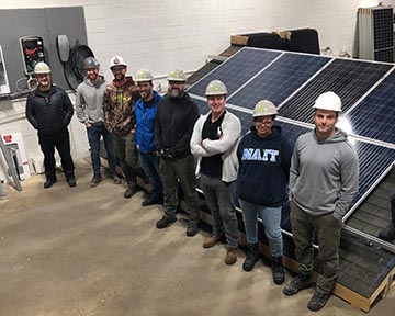 Workers lined up in front of solar panels.