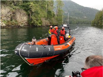 An orange rescue boat has three people on it durng training of the Coastal Nations Coast Guard Auxilary