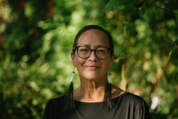 Dr. Nel Wieman stands in front of leafy trees