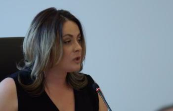 A young woman speaks into a microphone during a press conference.