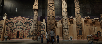 Totem poles fill the photo with a family looking up at them.