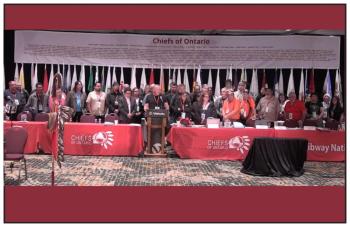 Chiefs of Ontario stand behind a man speaking at a podium.