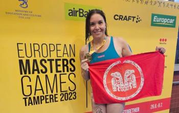 Gold medal for swimmer who holds up her hardware and the Haida Gwaii flag.