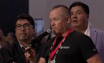 Three men stand around a microphone.