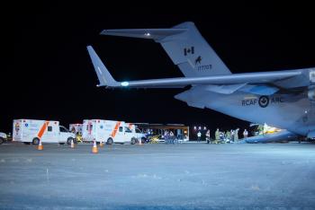 An airplane on the tarmac with two ambulances parked beside it.