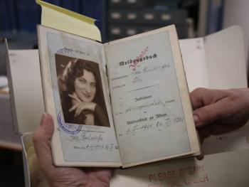 A small book is open to a black and white photo of a young woman.