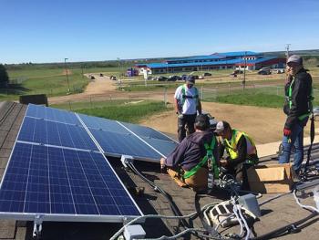 People are working on a rooftop installing solar panels.