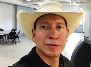 A man in a white cowboy hat is photographed. 