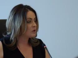 A young woman speaks into a microphone during a press conference.