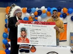 Two men are holding up a enlarged Treaty Card with with a sports headshot of Evander Kane. 