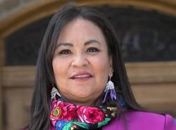 A woman stands outside a legislature building and looks at the camera.