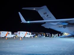 An airplane on the tarmac with two ambulances parked beside it.