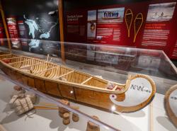 A birchbark canoe is displayed in a case.