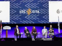 People sit on chairs on a large conference stage underneath banners that read Destination Original International Tourism.