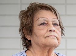 Photo is of an elderly woman with short brown hair streaked with blonde.